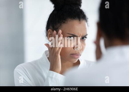 Gestresste junge afroamerikanische Frau, die sich Sorgen um die ersten Falten macht. Stockfoto