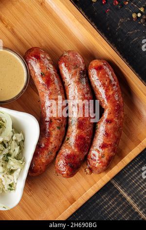 Drei gegrillte Würstchen auf Holzbrett Stockfoto