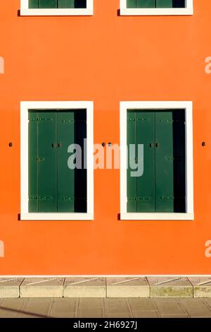 Zwei orangefarbene Fenster mit geschlossenen grünen Fensterläden, Insel Pellestrina, Lagune von Venedig, Italien Stockfoto