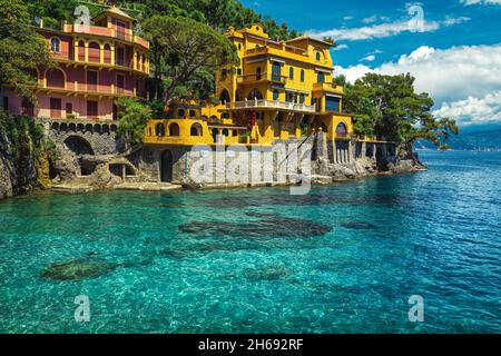 Niedliche bunte Häuser am Meer auf den Klippen mit atemberaubendem azurblauen Strand, Portofino, Italien, Europa Stockfoto