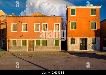 Viele Fenster in zwei alten Häusern orange mit geschlossenen Fensterläden, Pellestrina Insel, venezianische Lagune, Italien Stockfoto