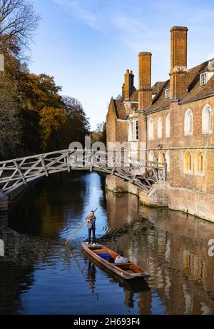 Punting Cambridge UK; eine Frau, die im Herbst unter Isaac Newtons Mathematical Bridge am Queens College Cambridge University, Cambridge England, puntet Stockfoto