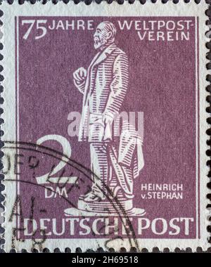 DEUTSCHLAND, Berlin - UM 1949: Eine Briefmarke aus Deutschland, Berlin in violetter Farbe mit dem Postmeister Heinrich von Stephan Text: 75 Jahre Welt Stockfoto