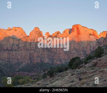 Zion National Park, Utah, USA. Blick über Wüstenpinsel zu den Türmen der Jungfrau, Sonnenaufgang, dem Hexenkopf und Opferaltar prominent. Stockfoto