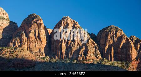 Zion National Park, Utah, USA. Panoramablick auf die drei Marys, benachbarte Sandsteinsäulen mit Blick auf das Dorf Springdale, am frühen Morgen. Stockfoto