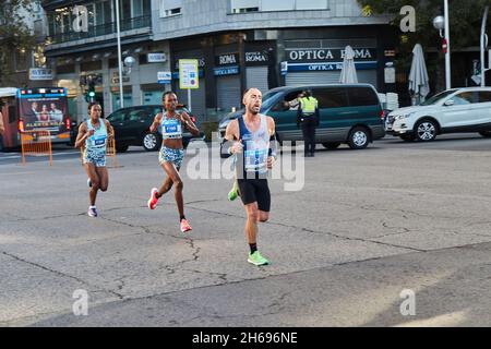 Eine Gruppe von Läufern während des Halbmarathons in Madrid 2021, bestehend aus einem weißen Mann und zwei schwarzen Frauen. Im Menschen sieht man das Gesicht des Leidens. Horizontal Stockfoto