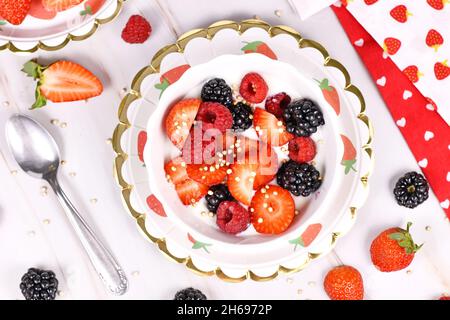Draufsicht auf eine Joghurt-Schüssel mit Erdbeer-, Himbeer- und Brombeerfrüchten und gepufftem Quinoa Stockfoto