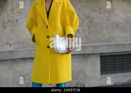 Mailand, Italien - 24. September 2021: Straßenkleidung, modische Frau in gelbem Prada-Outfit, weiße Tasche in Mailand, Italien. Stockfoto