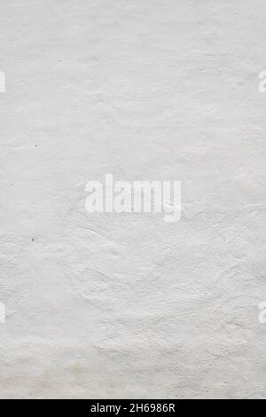 Antike massive Steinwand mit Gips und weiß lackiert. Strukturierte, unebene, raue Oberfläche. Referenzmaterial für Künstler. Stockfoto