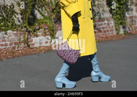 Mailand, Italien - 24. September 2021: Modische Frau im Street-Style-Outfit trägt einen gelben übergroßen Mantel, ein schwarz-pinkfarbenes Muster der Cleo-Handtasche Stockfoto