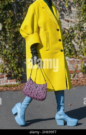 Mailand, Italien - 24. September 2021: Modische Frau im Street-Style-Outfit trägt einen gelben übergroßen Mantel, ein schwarz-pinkfarbenes Muster der Cleo-Handtasche Stockfoto