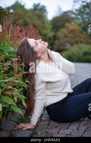 Weiße junge Frau in weißem Pullover im Park Stockfoto