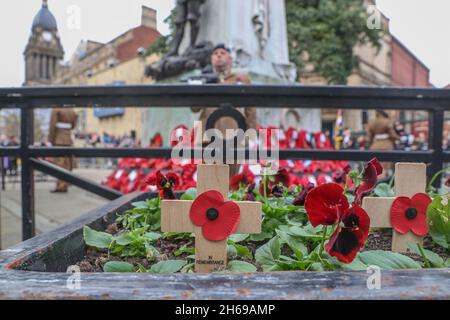 Ein Kreuz mit einem Mohnblumen liegt in einem Blumenbeet unter dem Kriegsdenkmal während der Gedenksonntagsfeiern am 14. November 2021 im Kriegsdenkmal in Victoria Gardens Leeds, West Yorkshire, Großbritannien. Am 11/14/2021 in Leeds, Großbritannien. (Foto von Mark Cosgrove/News Images/Sipa USA) Stockfoto