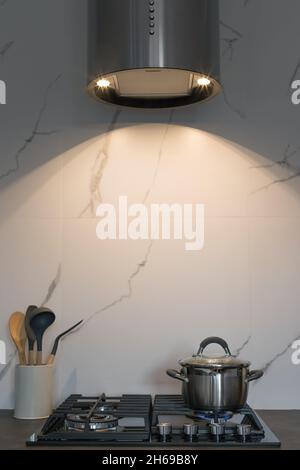 Metallkochfeld auf Gasherd mit silberner Küchenhaube Stockfoto
