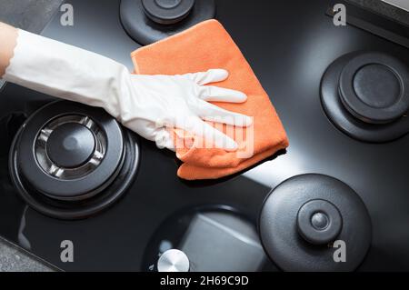 Person Hand hält Lappen und wischen Gas Herd oben Stockfoto