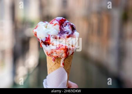 Hand hält köstliche schmelzende Erdbeer-Gelato-Eis-Kegel Stockfoto