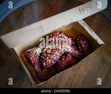 Würzige koreanische gebratene Hühnerflügel und Trommets in einer Take-Away-Box. Traditionelles asiatisches Rezept. Stockfoto