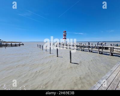 Podersdorf, Österreich - 09. Mai 2021: Nicht identifizierte Personen auf dem Landungssteg mit Leuchtturm am Neusiedler See im Burgenland, bevorzugtes Reiseziel für den Urlaub Stockfoto