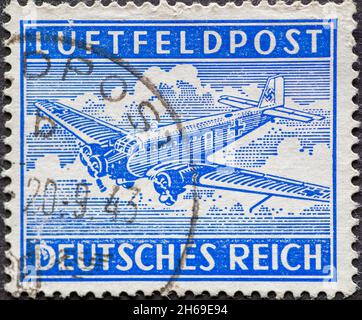 DEUTSCHLAND - UM 1942: Eine Briefmarke aus Deutschland, für die Feldpost via Luftpost, die das Flugzeug Junkers 52 in Blau zeigt Stockfoto