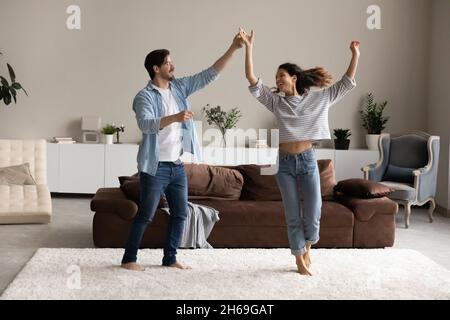 In voller Länge liebevolle junge Paar tanzen im Wohnzimmer zusammen Stockfoto