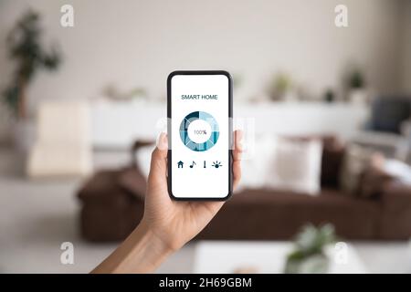 Nahaufnahme des Smartphones in weiblicher Hand, Smart-Home-Systemschnittstelle Stockfoto