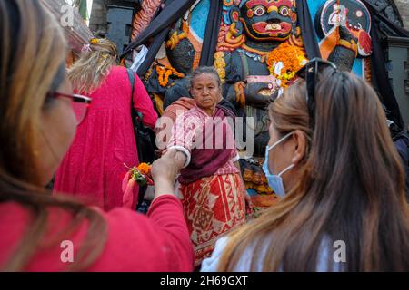 Kathmandu, Nepal - 2021. November: Pilger, die am 13. November 2021 in Kathmandu auf dem Durbar-Platz vor der Figur des Kala Bhairab Opfergaben, Stockfoto