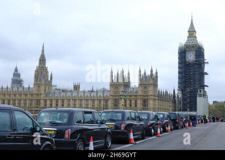 London, Großbritannien. November 2021. Dreihundert moderne und alte schwarze Taxis fahren am Remembrance Sunday auf der Länge der Westminster Bridge, um am jährlichen „Poppy Cabs“-Service teilzunehmen, der Veteranen kostenlose Fahrten zum Cenotaph-Gedenkgottesdienst in der Hauptstadt bietet. Schwarze Taxifahrer und Autoethnografen sind aus ganz London und dem Südosten angereist, um an einem seit 2009 laufenden Programm teilzunehmen. Kredit: Elfte Stunde Fotografie/Alamy Live Nachrichten Stockfoto