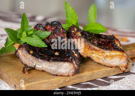 Nahaufnahme von gegrilltem Steak mit Minzstielen auf einem Holzbrett. Stockfoto