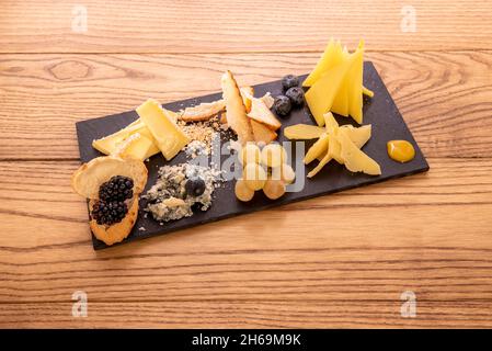 Große Tabelle mit verschiedenen Käsesorten und Beeren mit Trauben und Brombeeren als Tapas oder als Aperitif auf einem Holztisch zu nehmen Stockfoto