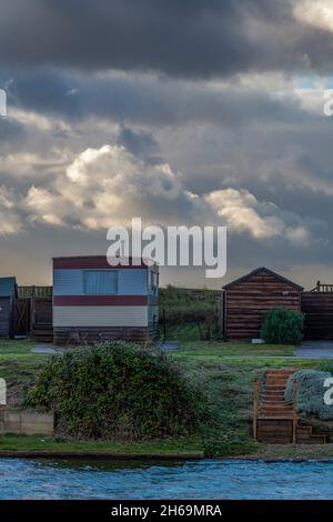 Strandhütten bei snettisham an der norfolk-Küste, stimmungsvolles launisches Bild von Strandhütten mit Platz für Kopien, stürmischer Himmel über Strandhütten norfolk. Stockfoto