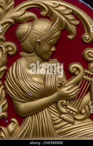 griechische oder römische klassische Figur in Relief auf der Oberfläche einer Wand geschnitzt, architektonische Dekoration in Form einer klassischen Frau spielen Lauge Harfe Stockfoto