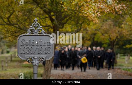 Magdeburg, Deutschland. November 2021. Eine Trauerprozession geht an einem Schild mit der Aufschrift 'Soldaten 1939/1945' ('Soldaten 1939/1945') auf dem Westfriedhof in Magdeburg vorbei. Am Gedenktag wurden die Opfer von Krieg und Tyrannei in ganz Sachsen-Anhalt mit Kranzniederlegungen und Gottesdiensten gedenkt. Quelle: Ronny Hartmann/dpa/Alamy Live News Stockfoto