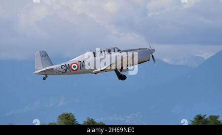 Rivolto del Friuli, Udine, Italien SEPTEMBER, 17, 2021 Metallgrau zwei Sitze im Tandem vintage Militärflugzeug zieht das Laufwerk nach dem Start mit Bergen im Hintergrund. Fiat G. 46 Stockfoto