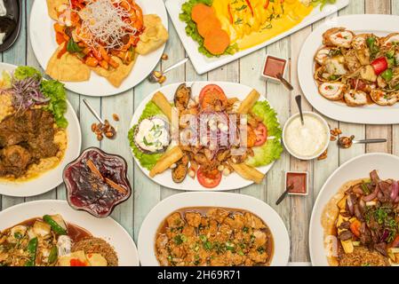 Auswahl an peruanischen Gerichten mit Gelee mit Meeresfrüchten, Wantan mit Gemüse, Hühnerrollen, violettem Dessert, Huancaina-Kartoffeln, lomo saltado Stockfoto