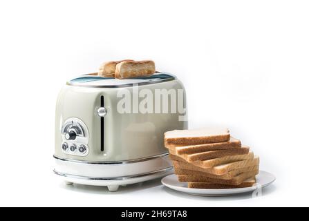 Retro-Toaster und ein geröstetes Brot mit mehreren Scheiben Weißbrot zum Frühstück zubereitet. Knuspriger Toast wird auf einem Teller verteilt, der auf w isoliert ist Stockfoto