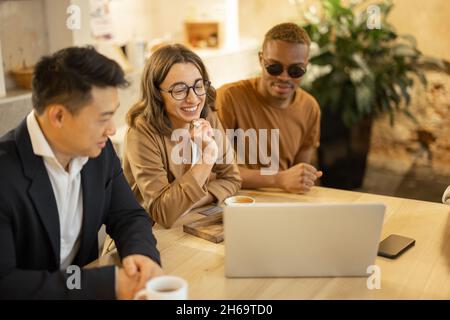 Das Business-Team schaut sich im Café etwas auf dem Laptop an Stockfoto