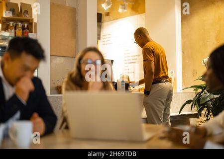 Das Business-Team schaut sich im Café etwas auf dem Laptop an Stockfoto