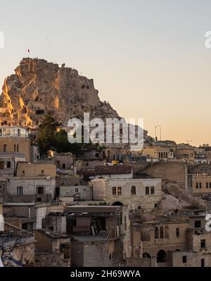 Eine vertikale Aufnahme des Schlosses Uchisar, das am Abend von alten Gebäuden umgeben ist, in Kappadokien, Türkei Stockfoto