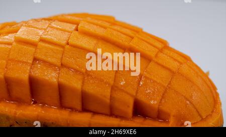 Auf hellgrauen Hintergrund isolierte Mango-Scheibe aus der Nähe zu Würfeln geschnitten Stockfoto