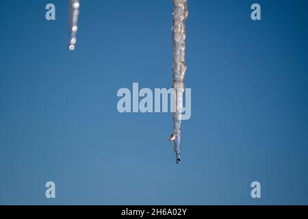 Gefrorene Eiszapfen isoliert auf blauem Himmel Hintergrund an einem sonnigen Frühlingstag, Nahaufnahme Stockfoto