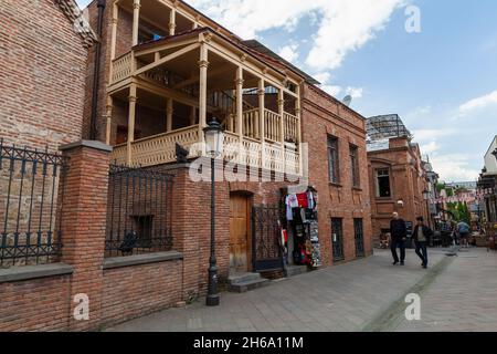 Tiflis, Georgien - 28. April 2019: Blick auf die alte Straße von Tiflis mit traditionellen Holzbalkonen gehen gewöhnliche Menschen auf die Straße Stockfoto