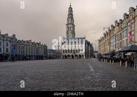 Arras, Frankreich - 4. November 2021: Marktplatz von Arras, Frankreich. Der Belfried von Arras, das zum UNESCO-Weltkulturerbe gehört, steht vor einem dunkelgrauen Himmel Stockfoto