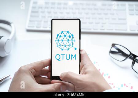 Russland Moskau 08.06.2021 Logo der Kryptowährung QTUM, Quantenkrypto-Münze im Mobiltelefon. Blockchain-Technologie zur Zusammenführung des Smart Contracts Stockfoto