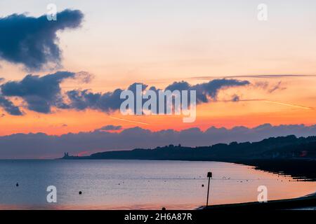 Der Morgenhimmel und der Cumulus mediocris wölken über den Zwillingstürmen der ruinierten Kirche in Reculver an der Küste von Kent mit Herne Bay Beach im Vordergrund. Stockfoto