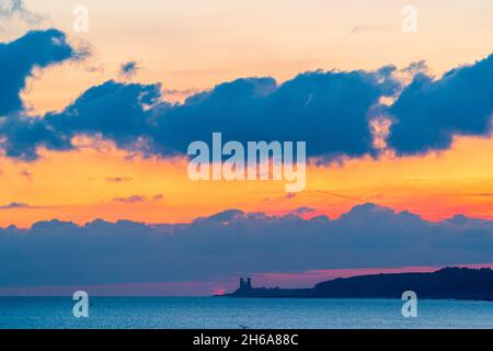 Der mauve und orange Morgenhimmel mit Cumulus mediocris Wolken über der Zwillingstürme Ruine der angelsächsischen Kirche in Reculver an der Küste von Kent. Stockfoto