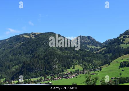 Ein Berghang in Zweisimmen, Schweiz. Atemberaubende, abfallende Landschaft mit einem nahezu klaren, blauen Himmel. Stockfoto