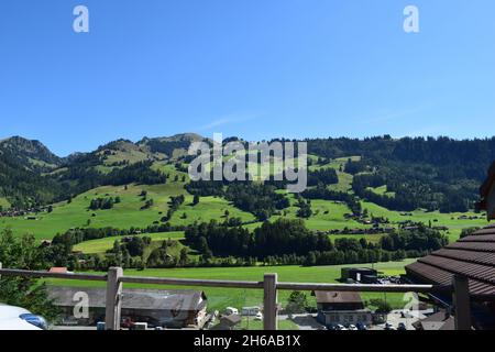 Ein Berghang in Zweisimmen, Schweiz. Atemberaubende, abfallende Landschaft mit einem nahezu klaren, blauen Himmel. Stockfoto