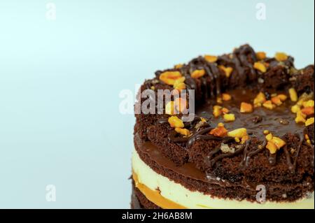 Seitenansicht von Schokoladenkuchen mit Karamell und Erdnüssen auf grünem Hintergrund. Stockfoto