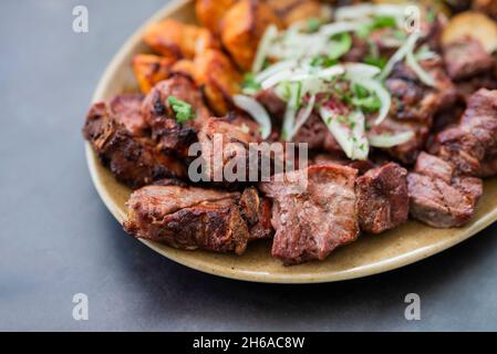 Fleischstücke Barbecue-Kebabs gegrilltes Schweinefleisch, Rindfleisch und Huhn auf einem Teller mit Zwiebeln in einem Restaurant Stockfoto