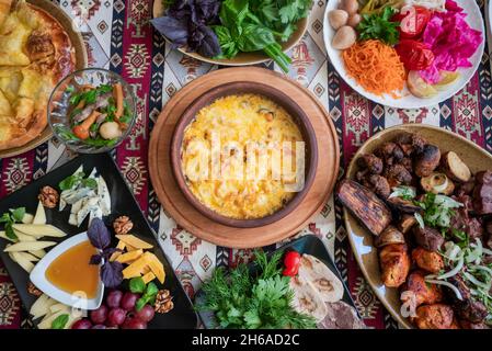 georgische und aserbaidschanische nationale Küche Suluguni Gerichte gebackenen adjarischen khachapuri, Pilze und Gemüse und Kräuter mit einem Teller mit verschiedenen Käsesorten Stockfoto